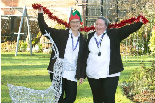 Nurses holding a tinsel behind a light up Reindeer