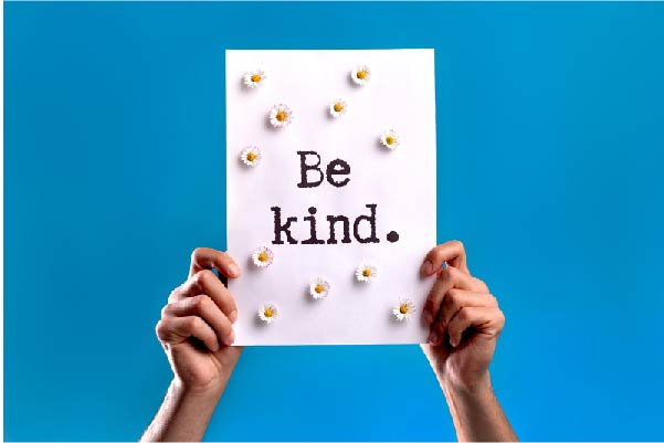 Hands holding a 'Be Kind' sign