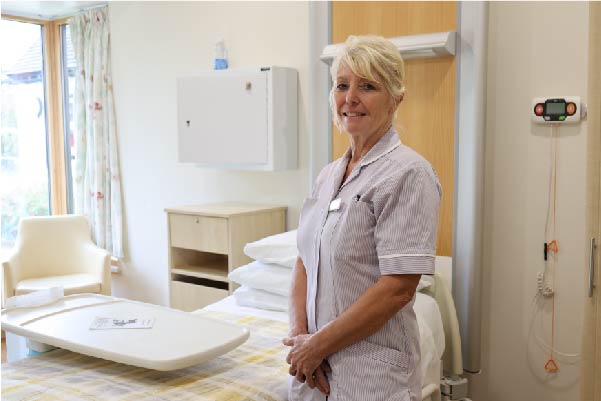 Health Care Assistant standing in a patients bed on the In-Patient Unit