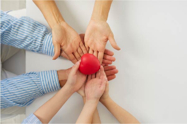 Hands together holding a plastic heart to showing kindness