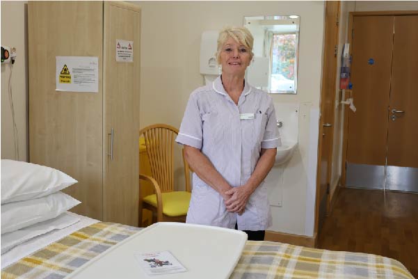 Health care assistant standing in room in the in-patient unit