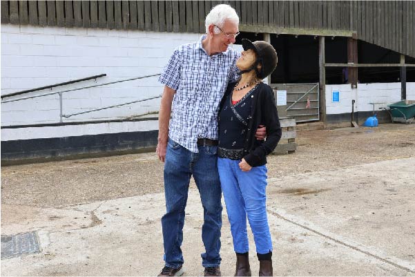 Female hospice patient smiling with her husband at a horse stable