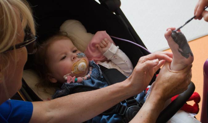 Penny smiling having her feet painted at Zoe's Place Baby Hospice