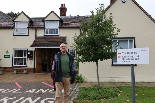 Brian £1000 Your Hospice Lottery winner standing in front of St Helena Hospice